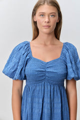 woman wearing a blue smocked dress with puff sleeves and a square neckline