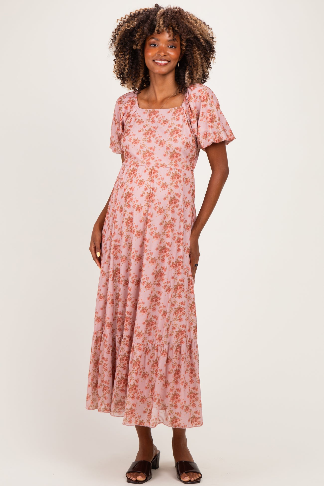 woman wearing a pink floral maternity maxi dress with short sleeves and a square neckline showing her baby bump