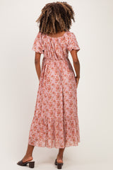 woman wearing a pink floral maternity maxi dress with short sleeves and a tiered skirt, showing a baby bump from the back
