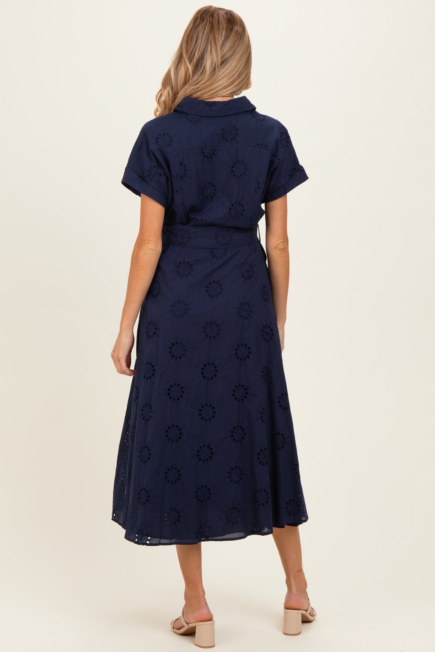 woman wearing a navy blue maternity wrap dress with floral embroidery and short sleeves, view from the back