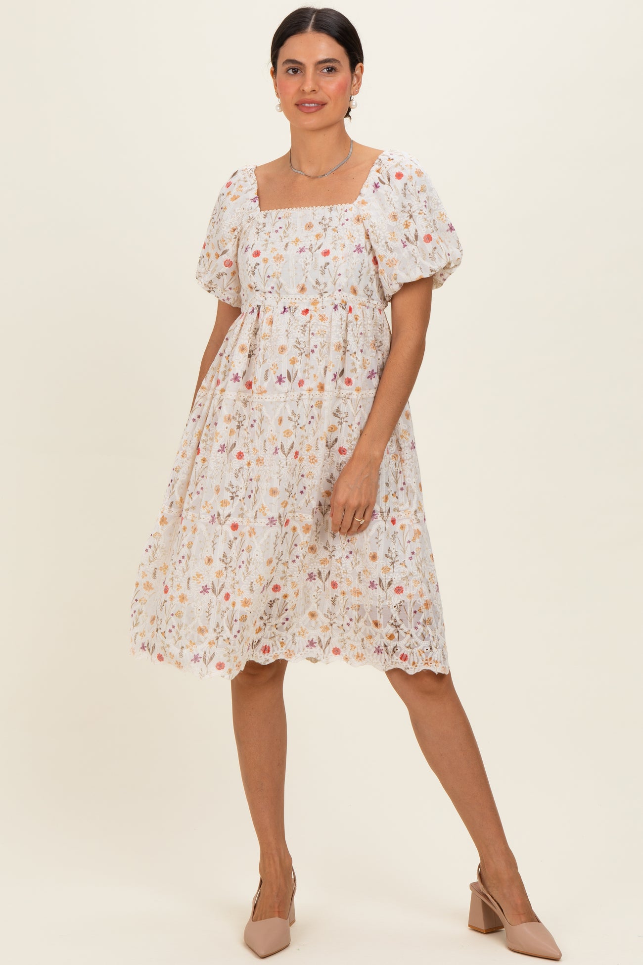 woman wearing a white floral embroidered short sleeve dress with a square neckline and puff sleeves