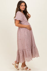 woman wearing a pink lace maternity dress with short flutter sleeves and holding her baby bump