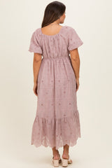 woman wearing a mauve floral embroidered maxi dress with short sleeves and a gathered waist, showing a baby bump