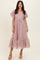 woman wearing a light mauve puff sleeve midi dress with a tiered ruffle hem and eyelet lace detailing