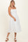 woman wearing a white eyelet midi dress with spaghetti straps and a tiered skirt, standing on a light background