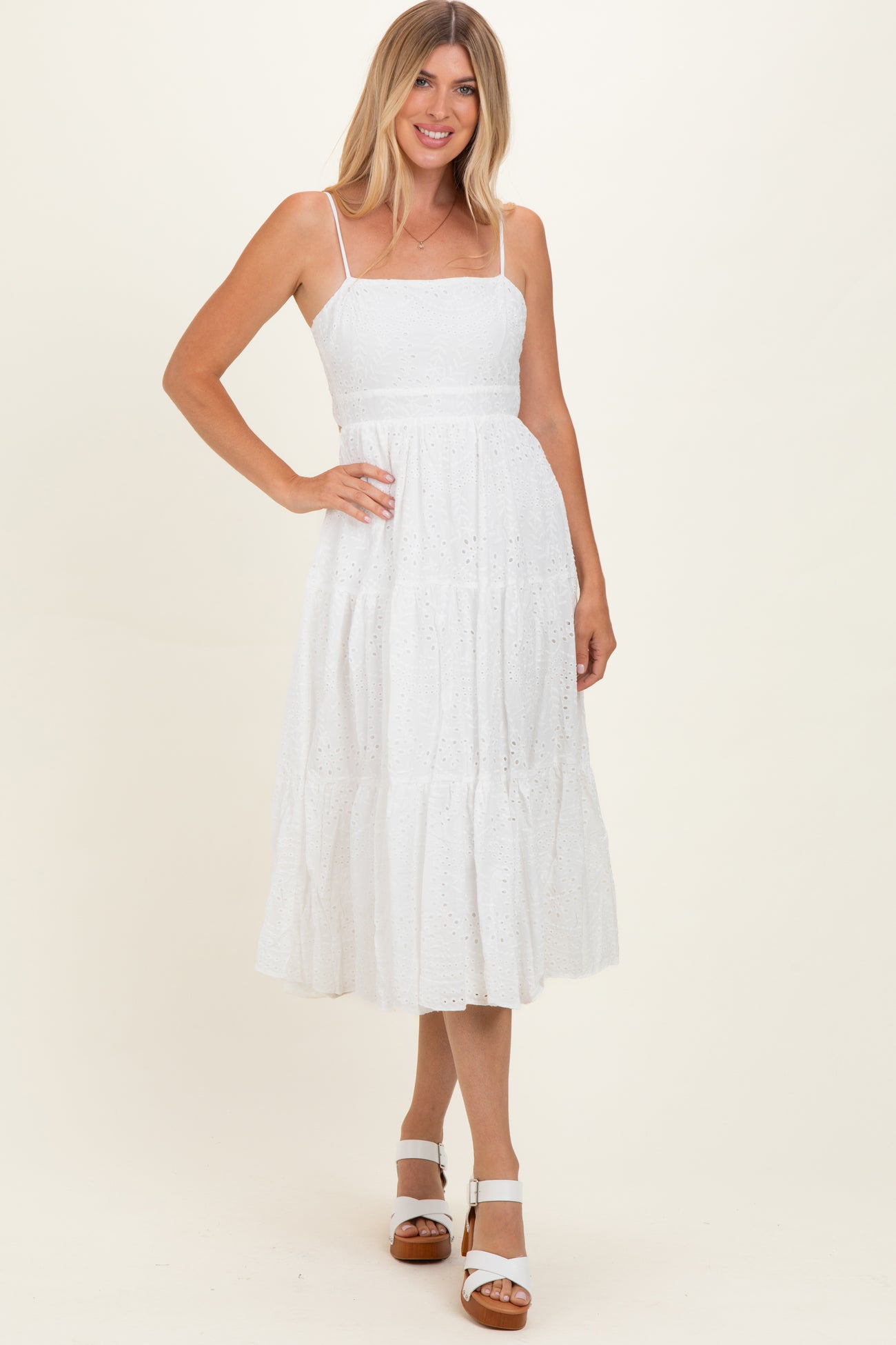 woman wearing a white tiered midi dress with spaghetti straps and eyelet lace details