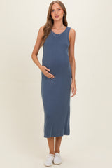 woman wearing a blue ribbed maternity dress, standing with her hand on her baby bump