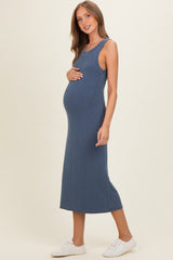 woman wearing a blue ribbed maternity dress and holding her baby bump