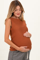 woman wearing a rust sleeveless maternity top and cradling her baby bump