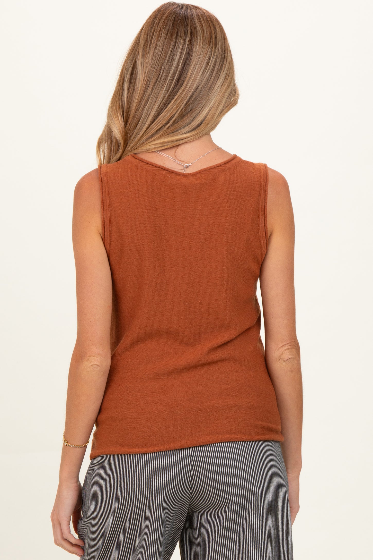 woman wearing a rust orange maternity tank top, view shows the back of the top