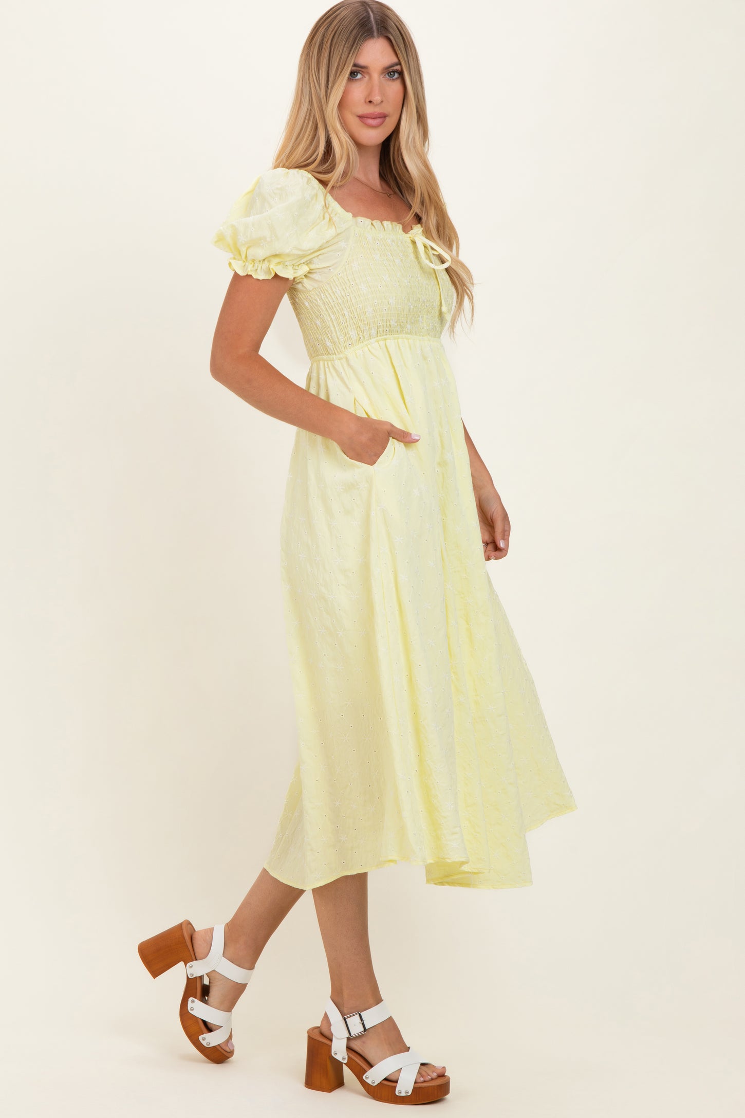 woman wearing a yellow puff sleeve midi dress with a smocked bodice and pockets