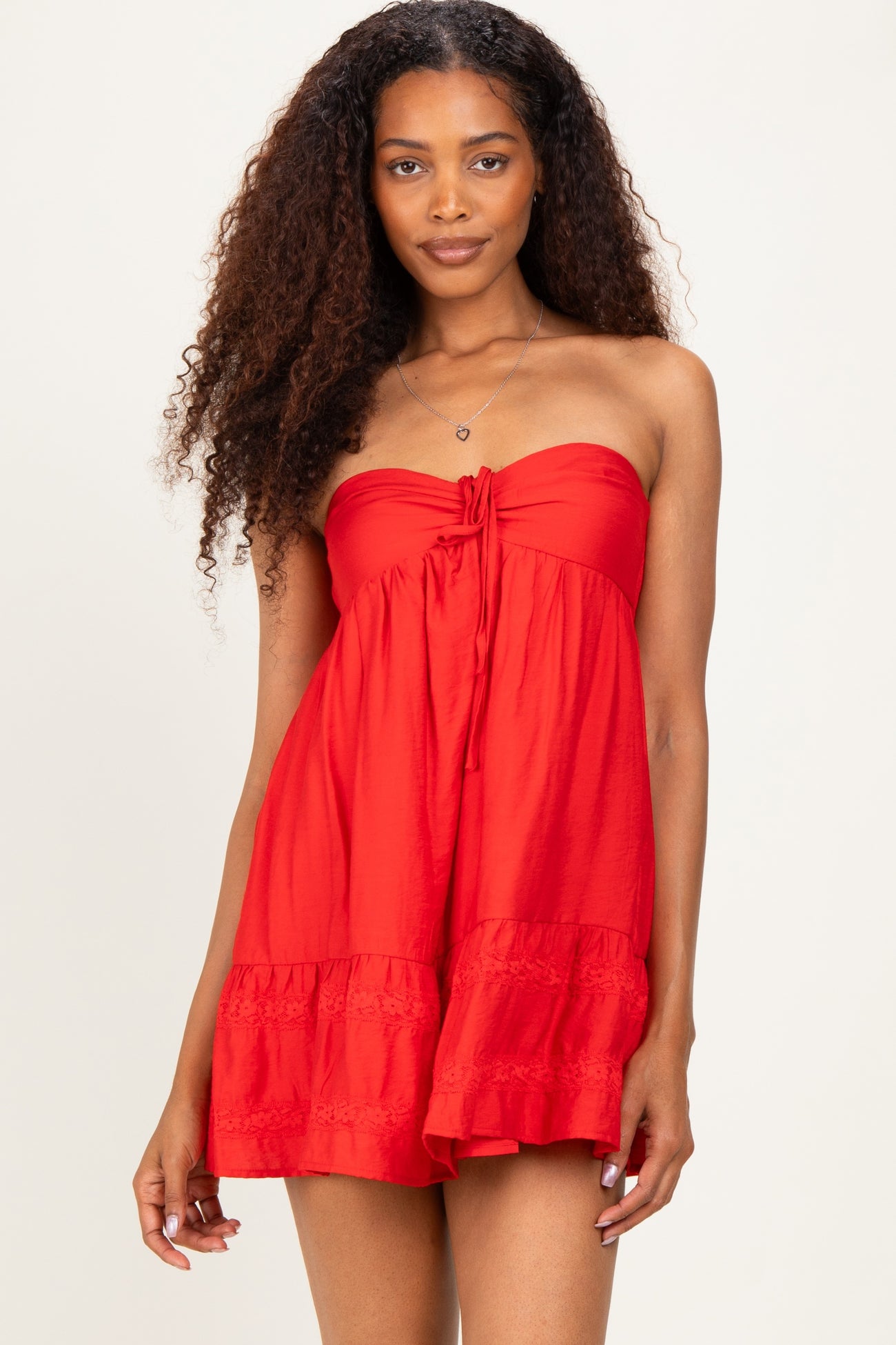woman wearing a red strapless sundress with a tie front and ruffled hem