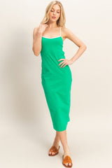 woman wearing a green slip dress with white straps and brown slide sandals