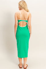 woman wearing a green midi dress with a white trim and an open back detail