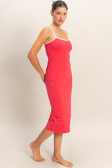 woman wearing a red slip dress with white straps, standing barefoot and facing the side