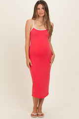 woman wearing a bright pink maternity dress with white straps and a visible baby bump