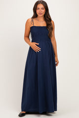 woman wearing a navy blue smocked maternity maxi dress and holding her baby bump