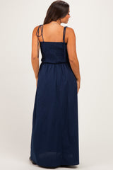 woman wearing a navy blue maternity maxi dress with a smocked bodice and adjustable straps, showing her back