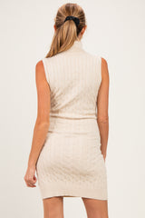 woman wearing a sleeveless cream cable knit maternity dress with a turtleneck and fitted waist from the back