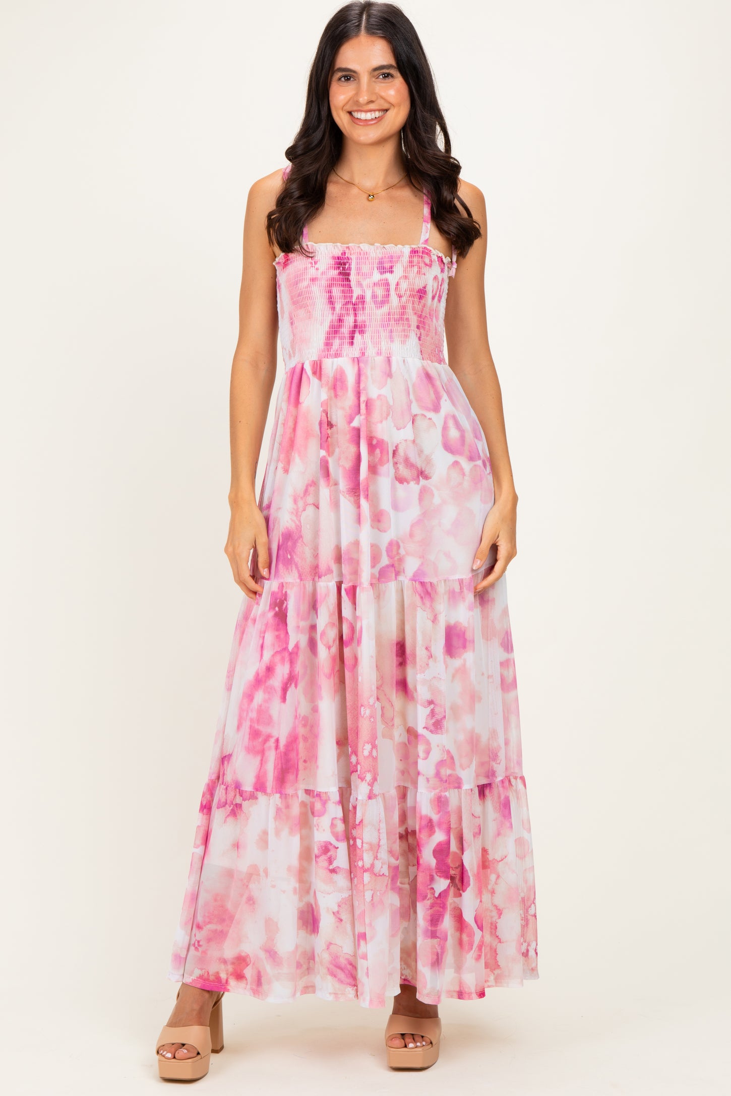 woman wearing a pink floral tiered maxi dress with a smocked bodice and spaghetti straps