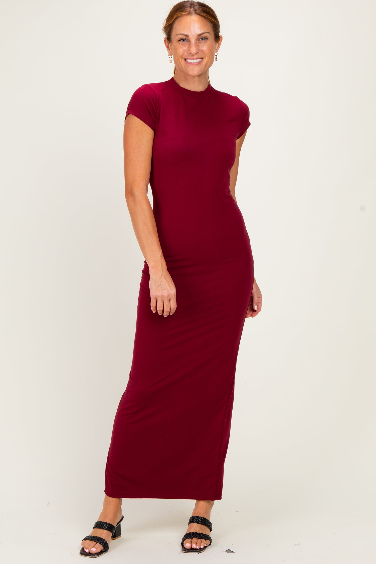 woman wearing a burgundy cap sleeve maxi dress, standing with a relaxed pose and smiling