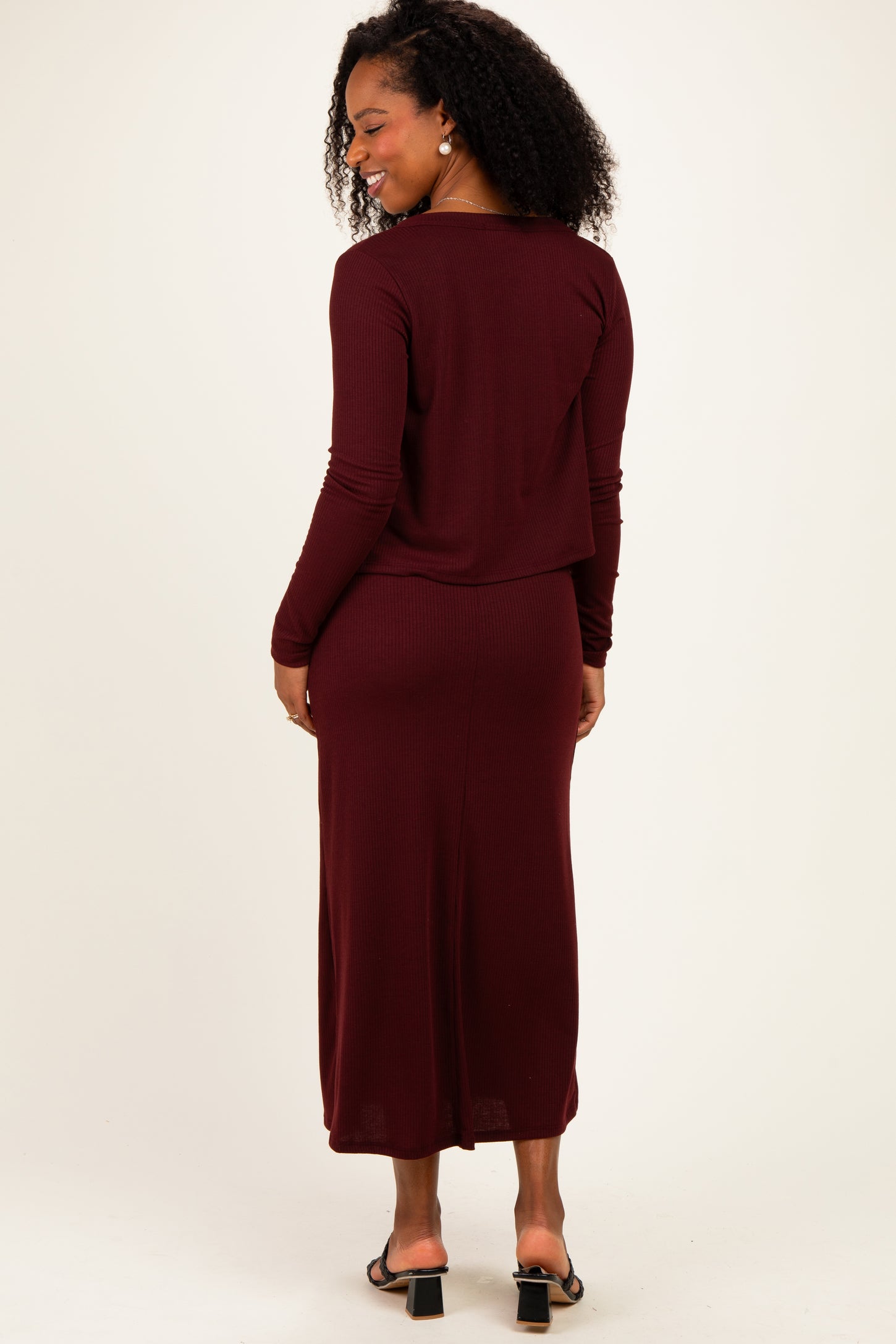 woman wearing a burgundy long sleeve ribbed dress with a relaxed fit and slit at the back