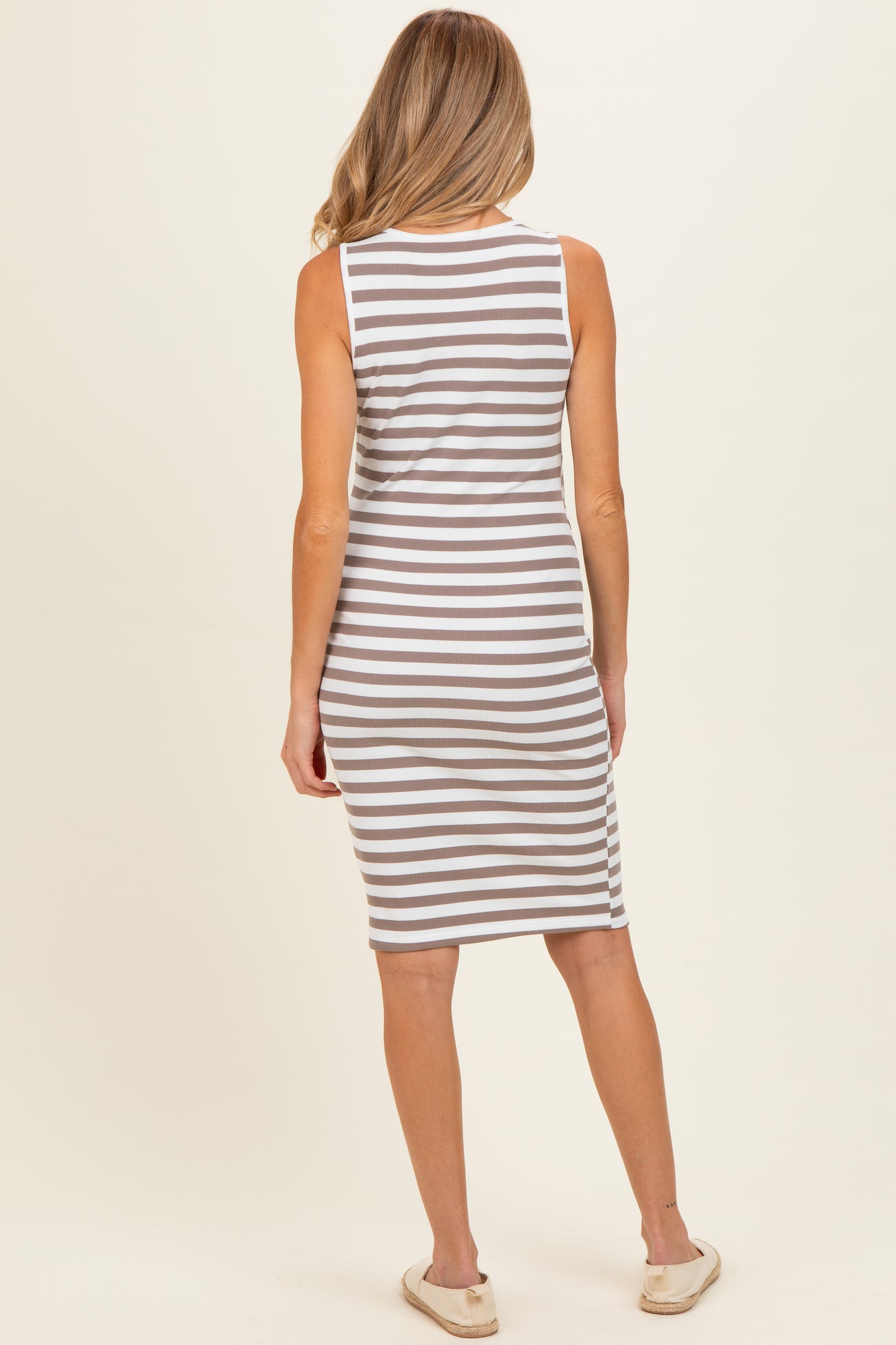 woman wearing a gray and white striped maternity dress, viewed from the back, with a fitted style and knee-length cut