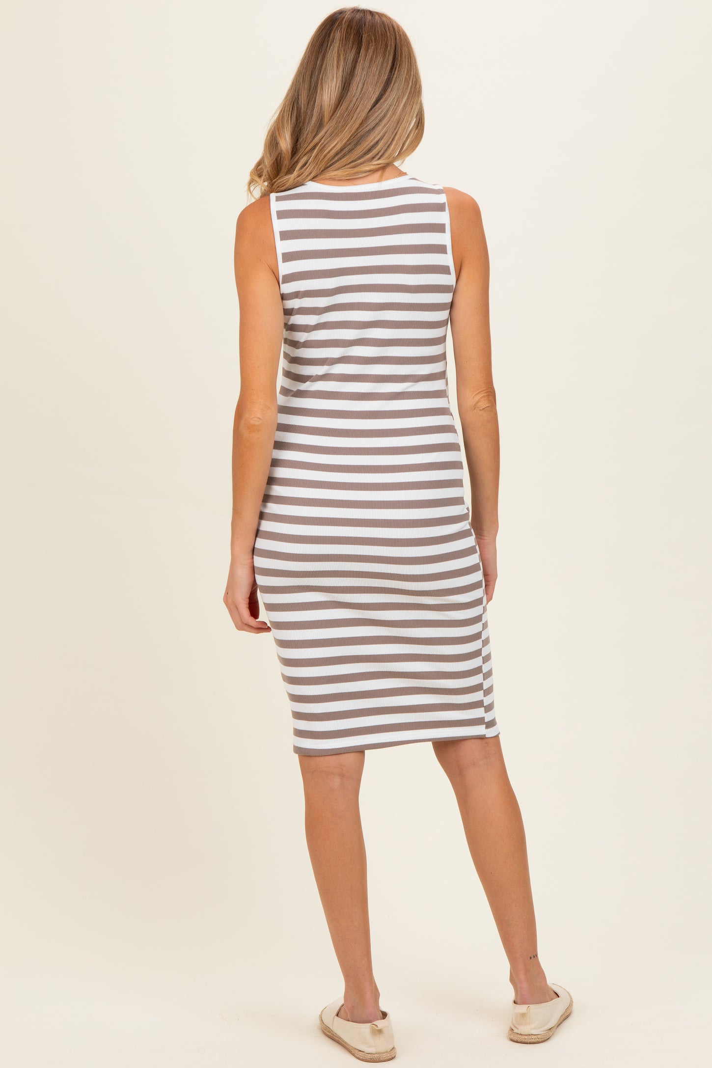 woman wearing a gray and white striped maternity dress, viewed from the back, with a fitted style and knee-length cut