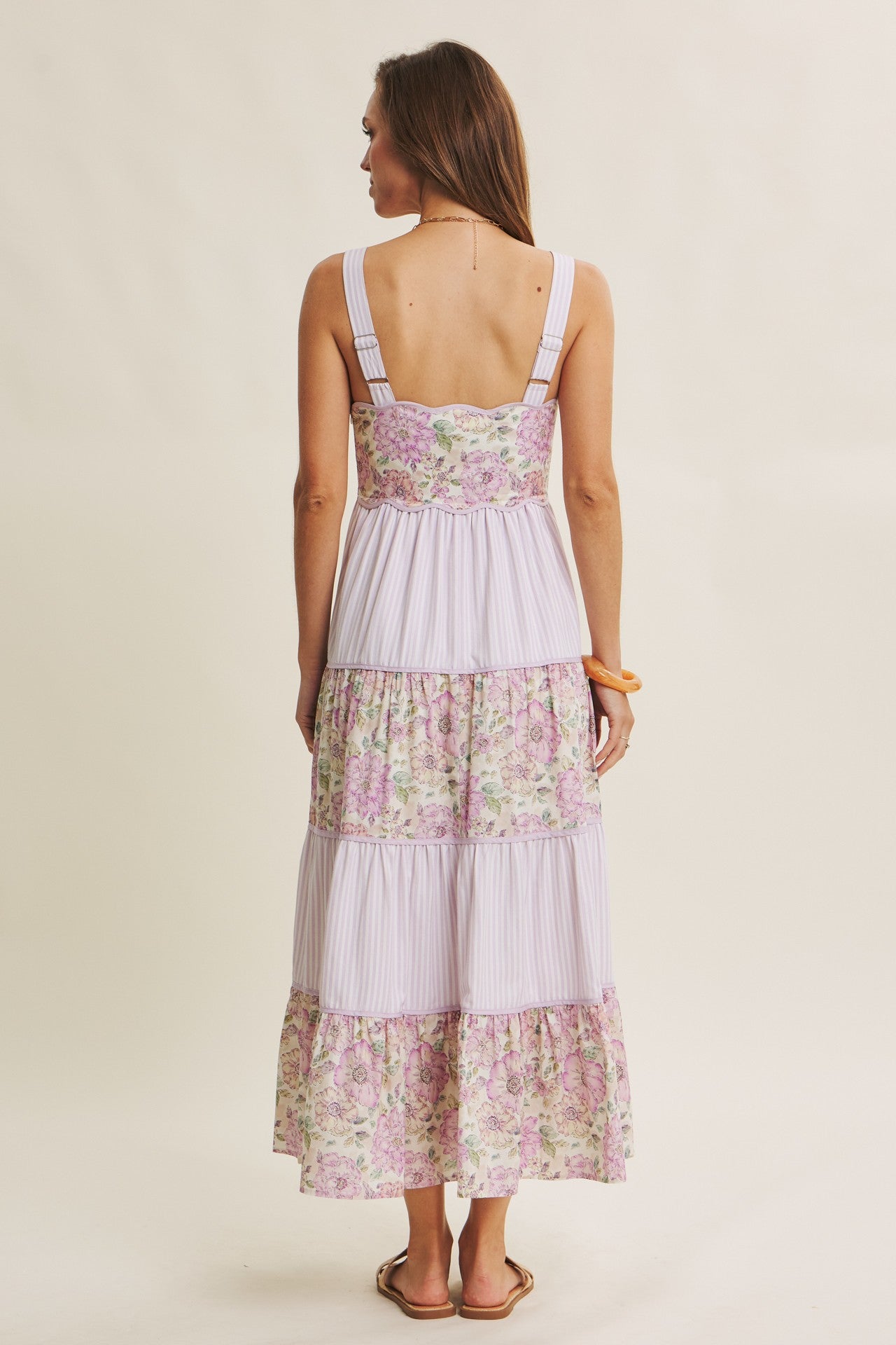 woman wearing a floral tiered maxi dress with adjustable straps, showing the back view