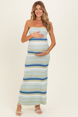 woman wearing a striped maternity maxi dress in green and blue, holding her baby bump