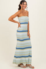 woman wearing a strapless striped maxi dress in light blue, green, and navy, smiling and posing with one hand on her hip