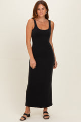 woman wearing a black sleeveless maxi dress with a scoop neckline and a fitted silhouette