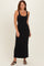 woman wearing a black sleeveless maxi dress with a scoop neckline and a fitted silhouette