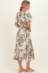 woman wearing a beige floral print maxi dress with short sleeves and a fitted waist, standing sideways