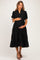 woman wearing a black maternity dress with short puff sleeves and a tiered skirt, holding her baby bump