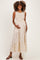 woman wearing a cream polka dot maternity dress with a tiered hem and holding her baby bump