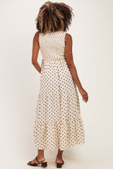 woman wearing a beige maternity dress with black polka dots and a tiered hem, showing the back view