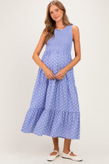 woman wearing a light blue maternity maxi dress with white polka dots and a smocked bodice, holding her baby bump