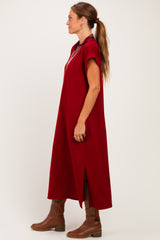 woman wearing a burgundy oversized dress with short sleeves and side slits, paired with brown knee-high boots