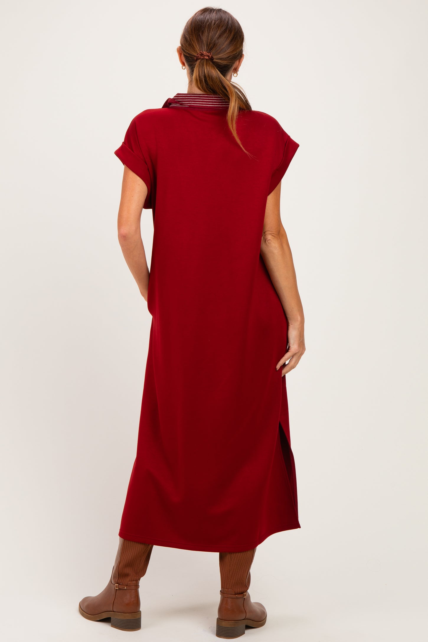 woman wearing a ruby red short sleeve dress with side slits and brown knee-high boots
