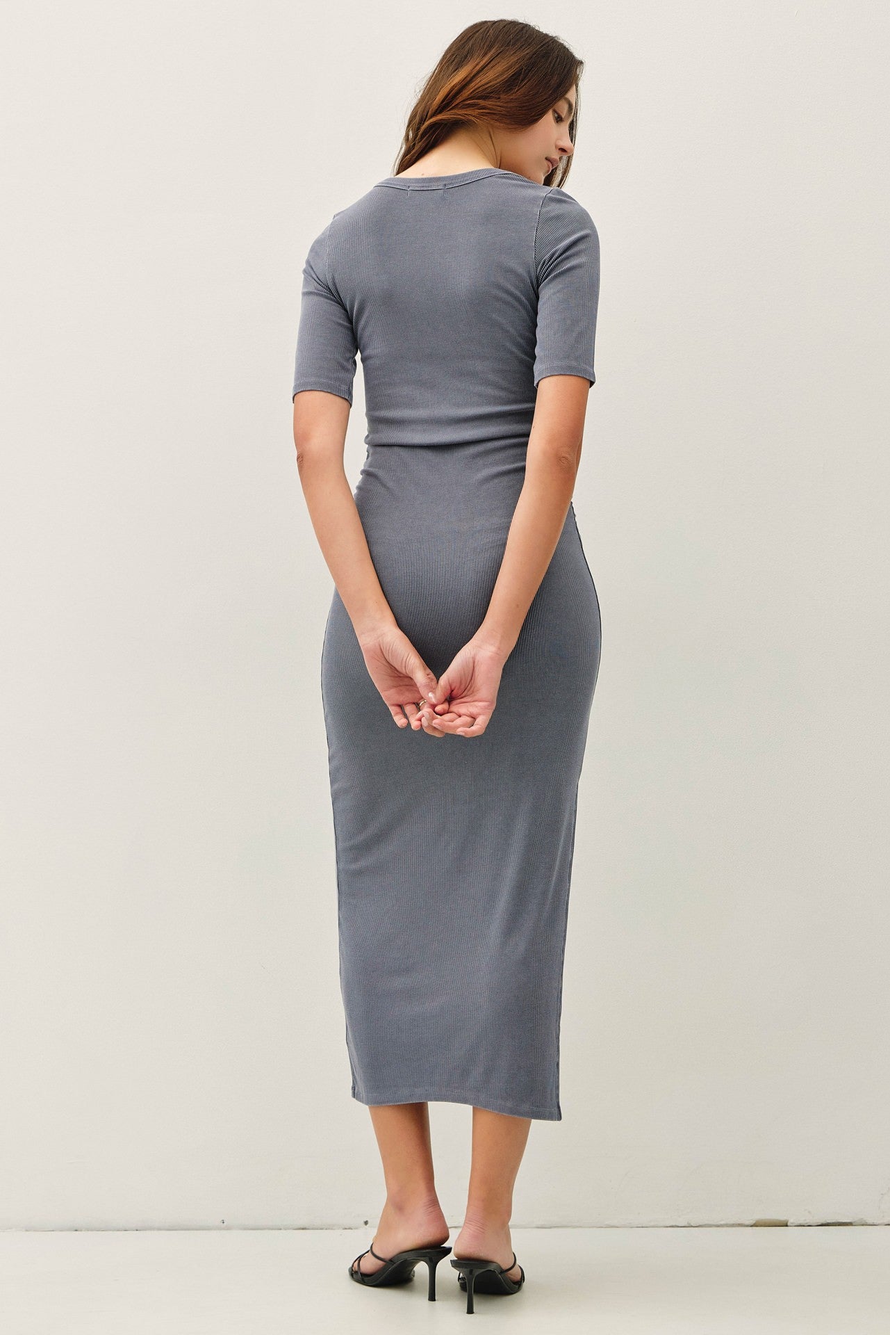 woman wearing a fitted gray ribbed midi dress with short sleeves, view from the back