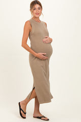 woman wearing a taupe sleeveless maternity dress and holding her baby bump
