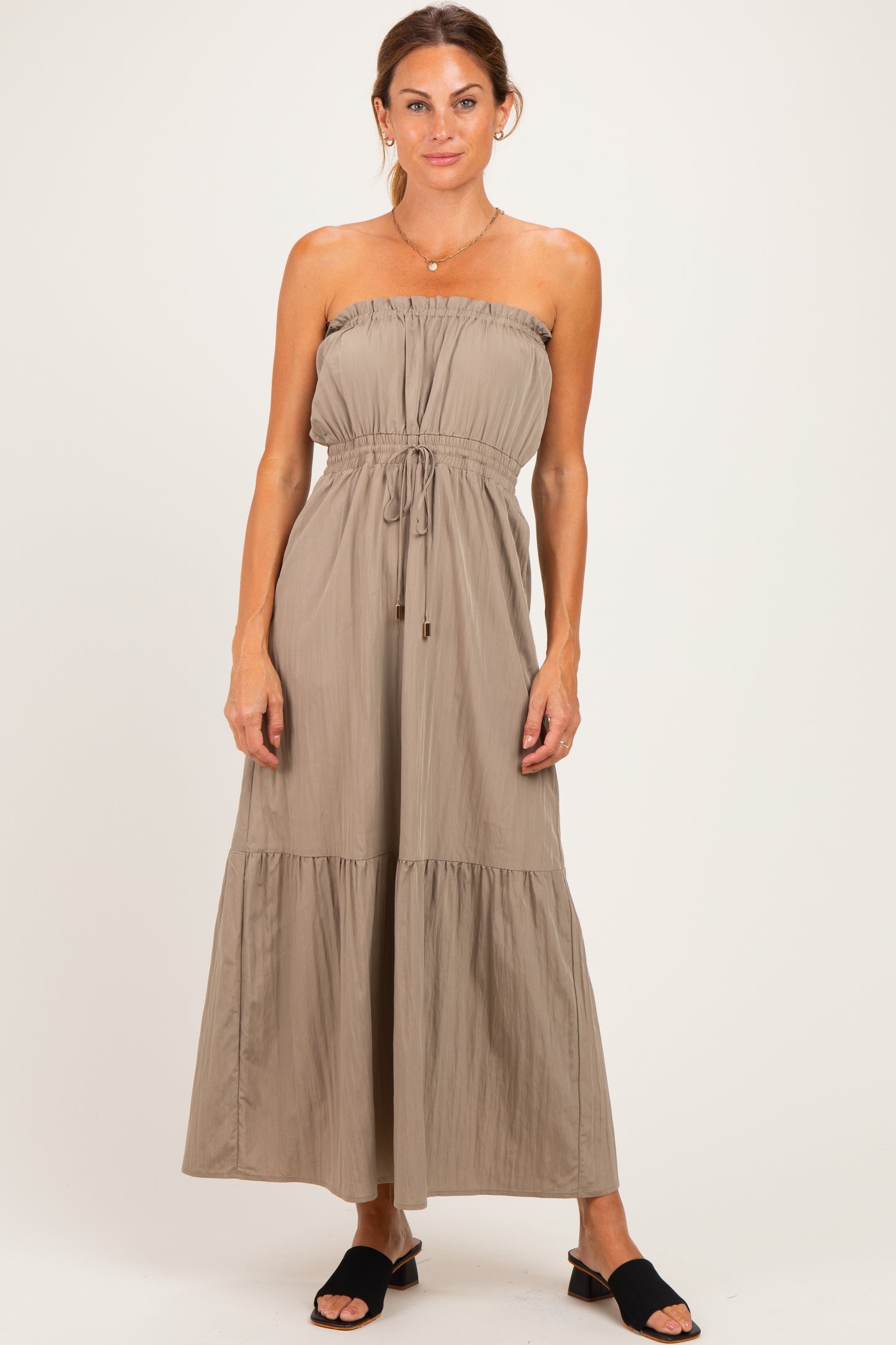 woman wearing a taupe strapless maxi dress with a drawstring waist and tiered skirt