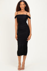 woman wearing a black off-the-shoulder ruched midi dress with a fitted silhouette and a side slit