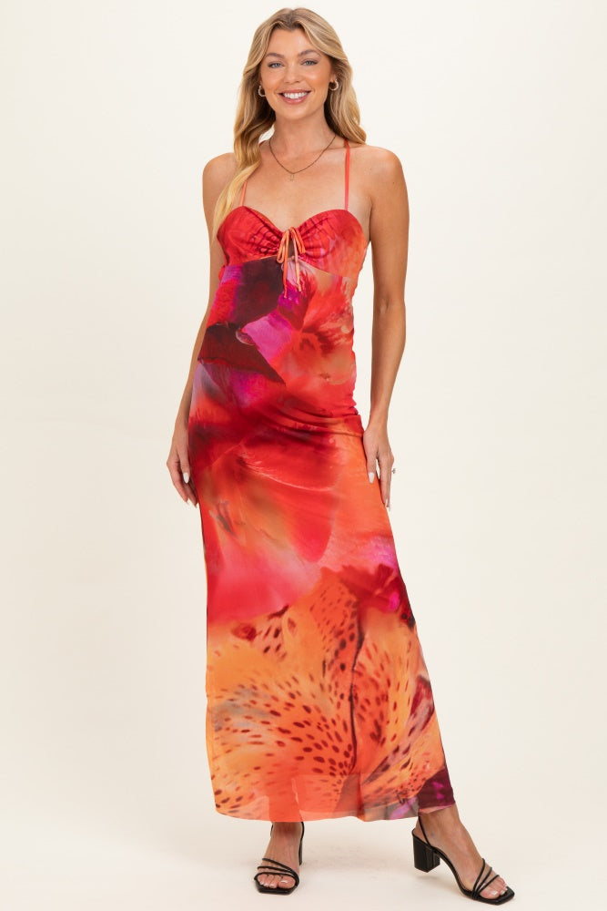 woman wearing a vibrant floral print maternity maxi dress with adjustable straps and a tie front detail