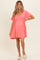 woman wearing a coral maternity dress with a v-neck and short sleeves, showcasing her baby bump