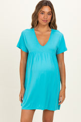 woman wearing a turquoise maternity dress with short sleeves and a v-neck, showing her baby bump