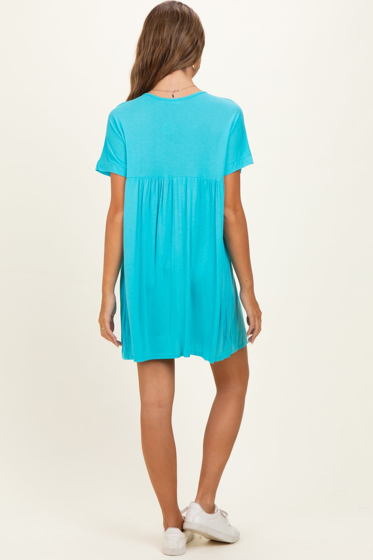 woman wearing an aqua blue short sleeve maternity dress with a relaxed fit and pleated back detail