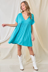 woman wearing a turquoise short sleeve swing dress and white cowboy boots