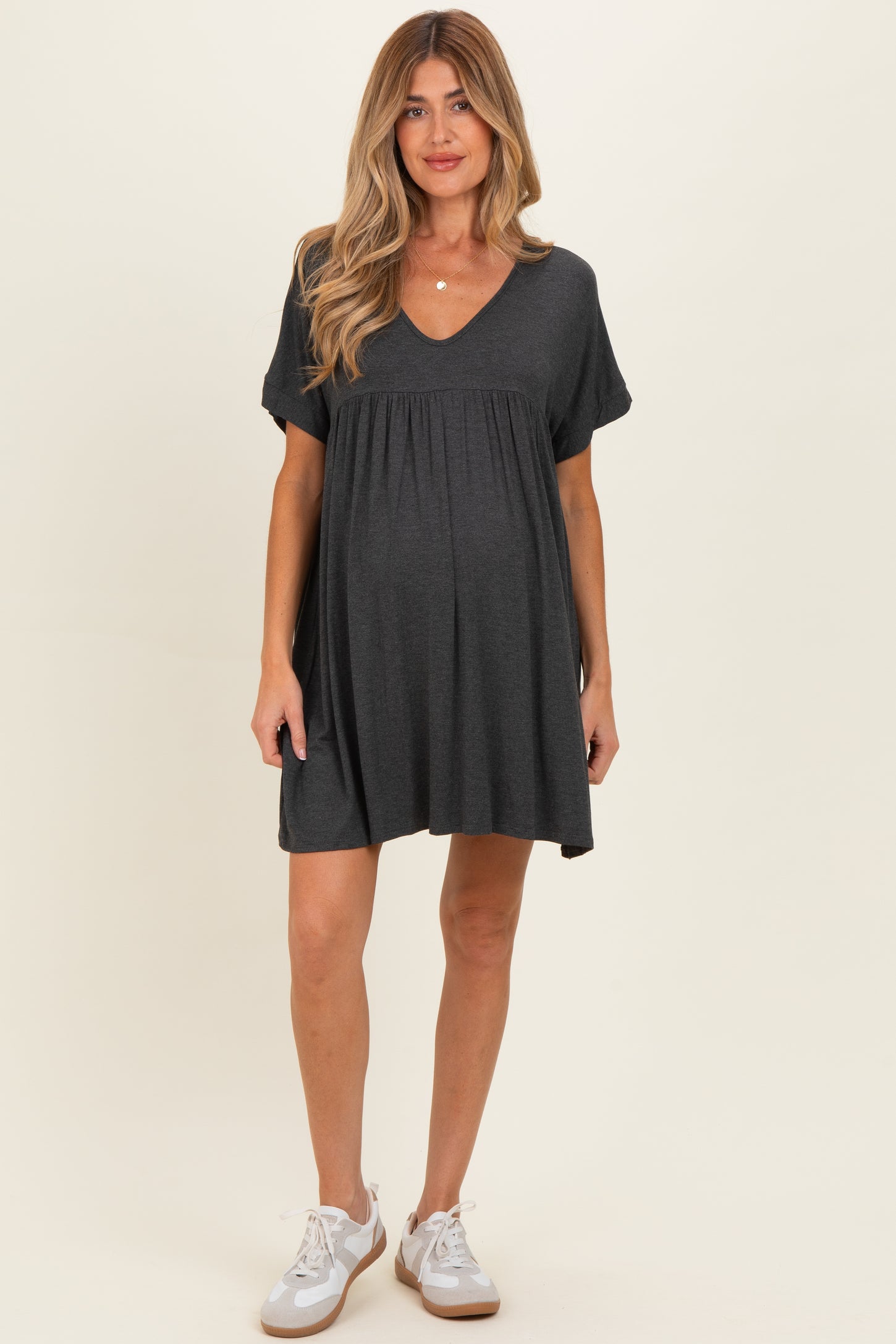 woman wearing a dark gray short sleeve maternity dress with a v-neck and baby bump visible